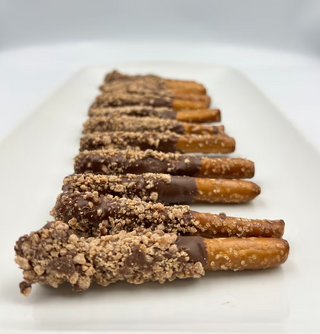 Row of chocolate-dipped pretzels on a white plate